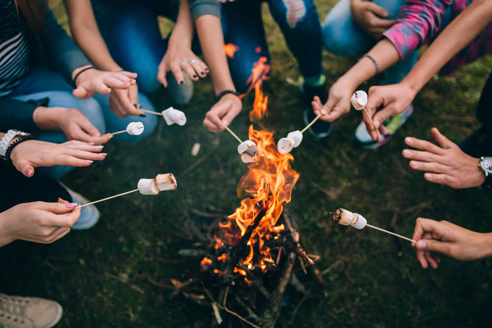 children hands roasting marshmallows at bonfire