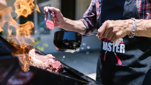 man hands holding a silicone brush and a pan preparing to moist a beef bbq