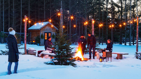 winter decor with a house and lights and people around a bonfire