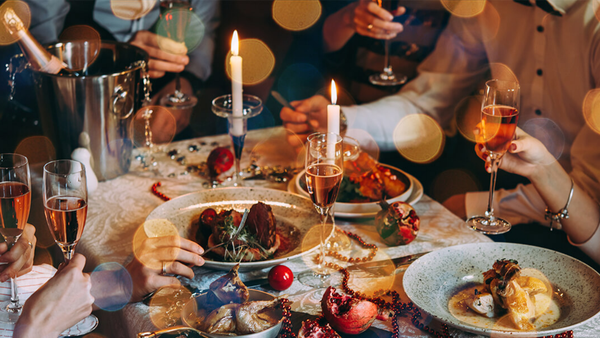 festive dinner table with candles and people holding glasses of wine