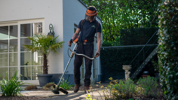 man cutting grass using a motorised tool