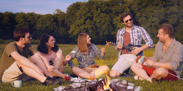 group of friends roasting marshmallows at bonfire singing