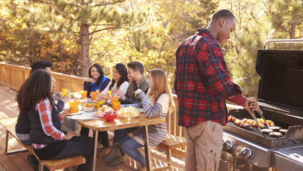 black man grilling with friends sitting at a table and having food and drinks